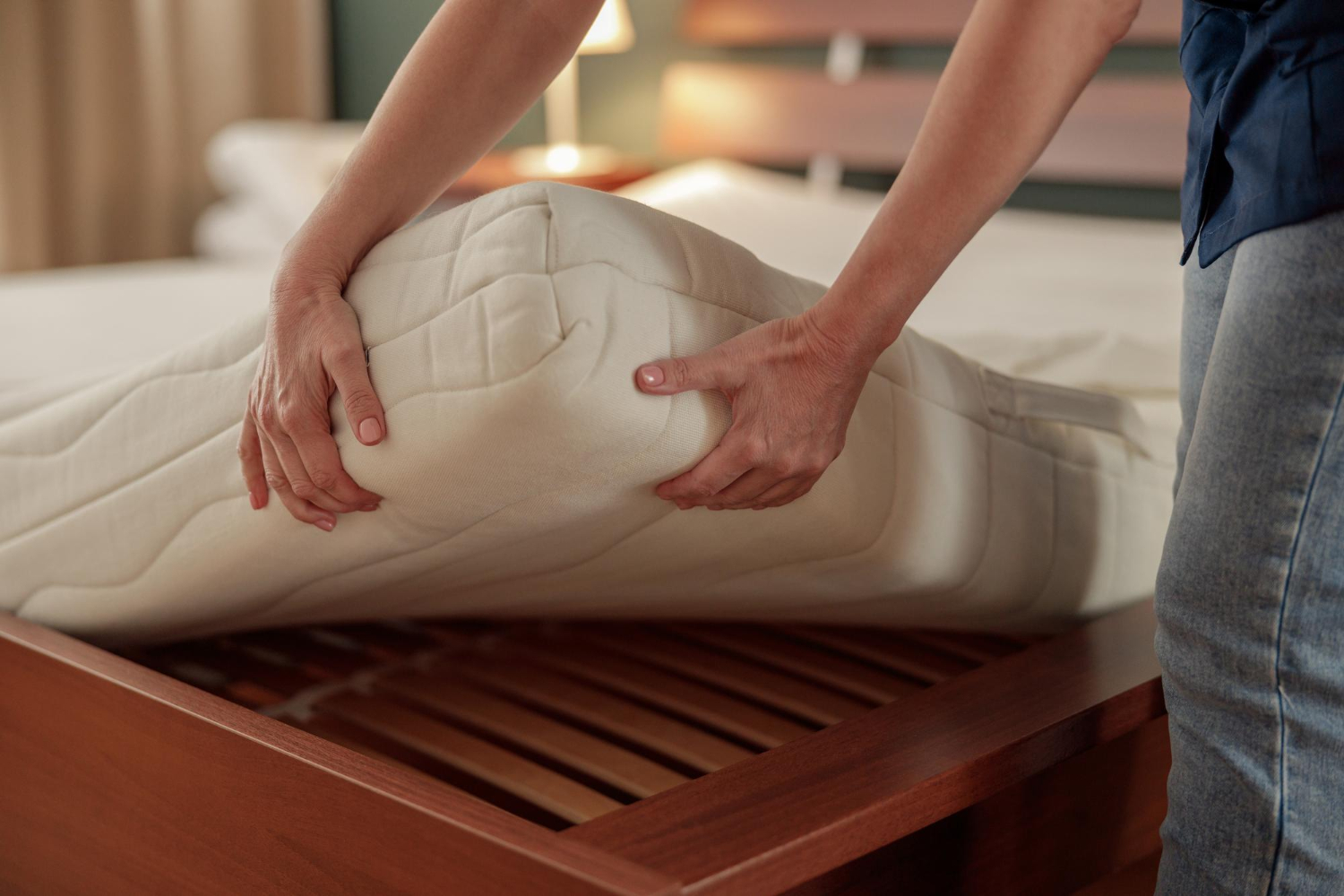 Une femme est en train de tester la fermeté d'un matelas dans une chambre à coucher.
